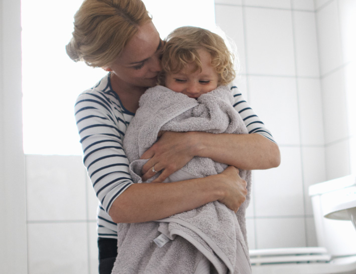 A mom hugging her son wrapped in a towel in the bathroom