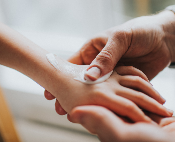 Someone applying lotion to the top of a hand